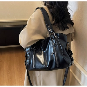 Détail du sac cabas en cuir noir brillant avec fermetures éclair et rivets argentés décoratifs