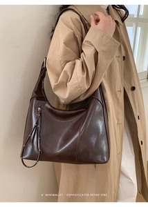 Detail of dark brown retro shoulder bag with decorative zipper and fringe on a model