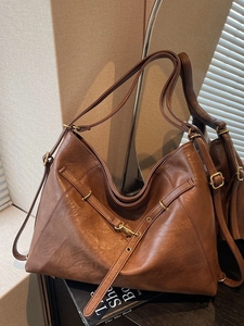 Brown vintage faux leather tote bag with decorative straps and adjustable shoulder handle