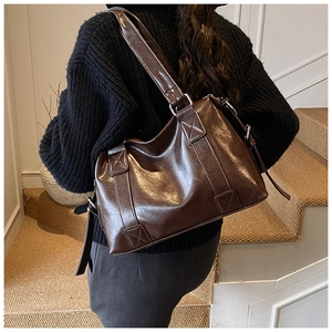Close-up of vintage dark brown leather tote with unique X-shaped stitching detail