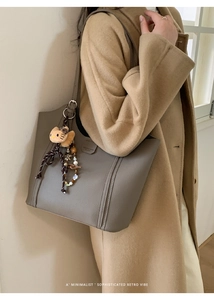Vue détaillée du sac cabas en cuir taupe avec coutures et breloque en peluche chat