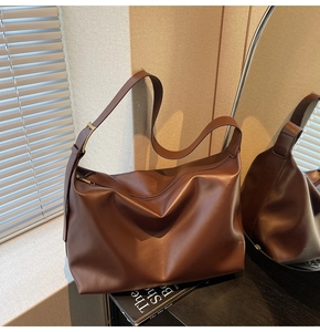 Close-up of brown soft leather tote bag with wide adjustable strap and gold hardware