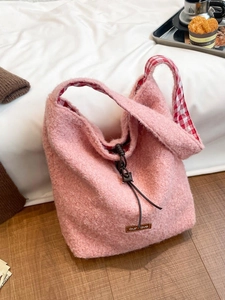 Pink plush tote bag with wool-like texture and red checkered lining in cozy winter setting