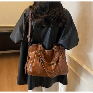Détails du sac cabas en cuir marron foncé avec larges anses et zips métalliques