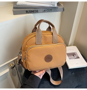 Detail of the yellow nylon crossbody bag with dual zipper and round bicycle logo patch