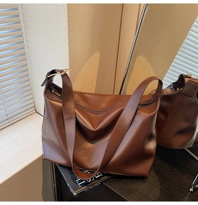 Detail of dark brown tote bag showing the wide strap and golden metal buckle adjustment