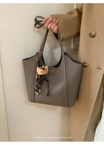 Détail du sac seau taupe avec texture en cuir et breloque peluche chat mignonne
