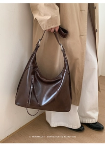 Street style view of a dark brown glossy hobo bag paired with a classic khaki trench coat