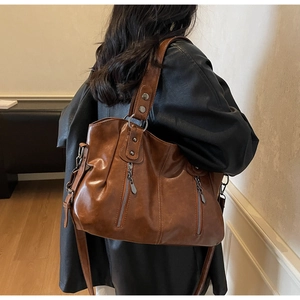 Détail d'un grand sac cabas vintage en cuir marron avec finitions zippées métalliques