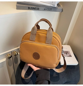 Detail of a mustard yellow canvas multi-way mini bag with leather logo and front zipper