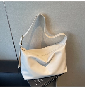 Detail of off-white tote bag showing soft leather texture and golden metal buckle