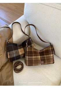 Détail des sacs sous le bras à carreaux vintage en laine avec sangles en cuir sur un canapé