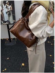 Detail of vintage brown leather tote bag showing smooth finish and wide shoulder strap