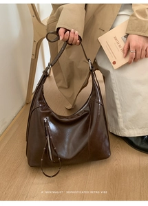Detail of dark brown glossy hobo bag featuring retro crescent curve and silver buckle