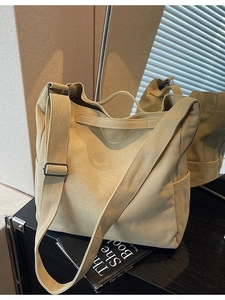 Minimalist khaki canvas crossbody bag with adjustable strap shown in a modern interior setting