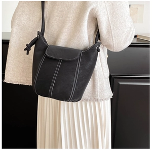 Detail of minimalist black bucket bag with contrast white stitching and knot shoulder strap