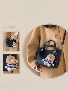 Close-up of black lychee grain leather bucket bag with a cute brown teddy bear charm