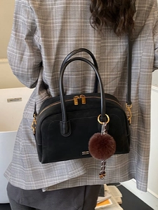 Vintage black pillow bag with gold zippers and plush charm shown on a grey blazer model