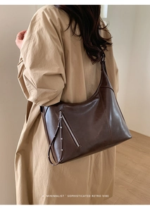 Detail of dark brown leather tote featuring a diagonal zipper with long puller cord