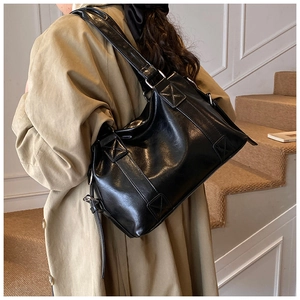Detail of vintage black glossy leather tote bag with wide adjustable shoulder straps