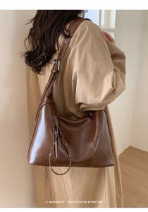 Minimalist caramel brown leather hobo bag with sleek vertical zipper detail on a shoulder
