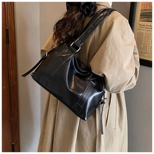 Detail of black vintage shoulder bag with drawstring showing texture on khaki trench coat