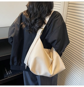 Dettaglio della grande borsa hobo crema con tracolla larga e fibbia in metallo bronzo