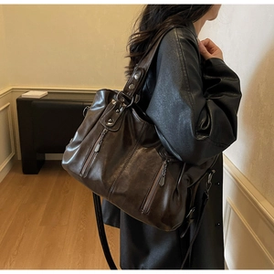 Détail d'un sac cabas marron foncé en similicuir brillant avec fermetures à franges