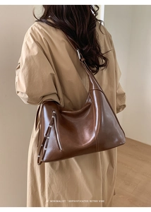 Detailed view of brown leather tote bag with side zipper and silver stud accents