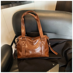 Close-up of vintage brown glossy leather tote bag with reinforced cross-stitching detail