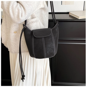 Macro detail of black leather bucket bag featuring distinctive white contrast stitching