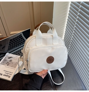 Detail of white nylon crossbody bag with brown leather logo and woven handles