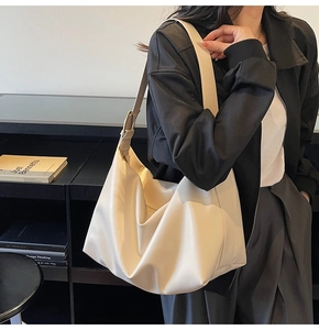 Dettaglio ravvicinato di una borsa tote beige in morbida pelle con fibbia dorata sulla tracolla