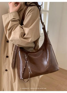 Detail of dark brown leather hobo bag with silver studs and vertical side zipper pocket