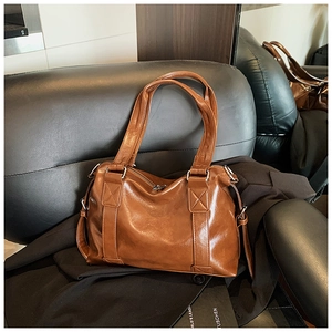 Detail of caramel glossy leather handbag with reinforced stitching and silver hardware