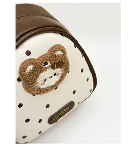 Detail of stitched bear embroidery and textured polka dot fabric on a versatile bag