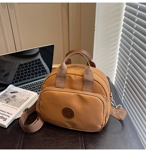Detailed view of caramel nylon crossbody bag with logo patch and wide strap