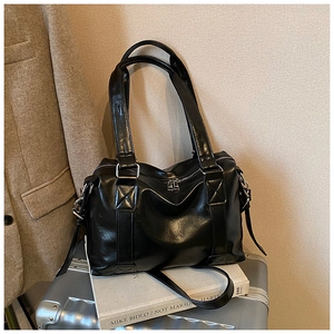 Detail of a large black leather tote bag featuring a sturdy handle and top zipper closure