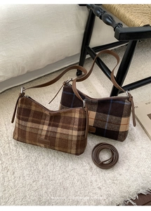 Détail de sacs à bandoulière à carreaux vintage avec des sangles en cuir marron sur un tapis doux