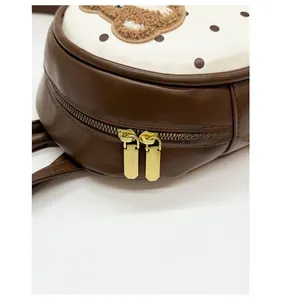Close-up of golden metal double zippers and textured brown faux leather on a backpack