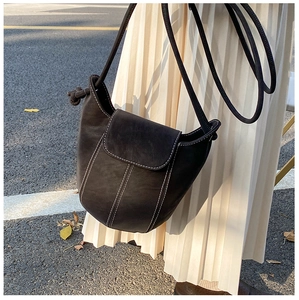 Detail showing vintage bucket bag with contrast stitching and leather strap on model