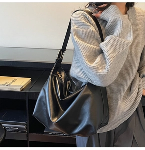 Modella che indossa una grande borsa hobo nera minimalista in un ambiente interno moderno