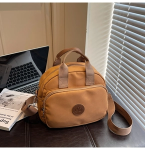 Detail of camel nylon crossbody bag with zipper compartments and leather logo patch