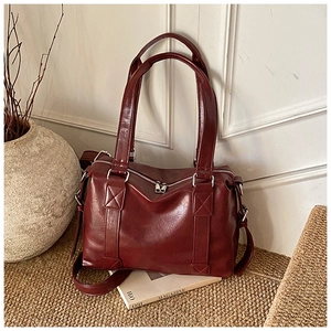 Close-up of deep red leather Boston bag with double zippers on a rustic minimalist background
