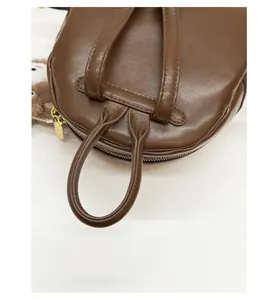 Detail view of reinforced shoulder straps on a brown leather bag with golden hardware