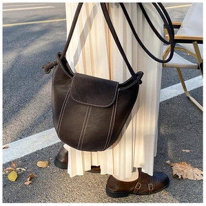 Detail of dark brown vintage bucket bag with white contrast stitching and knot detail