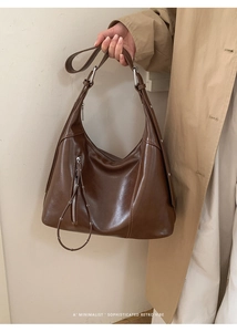 Detail of a brown oil-wax leather Hobo bag with vertical zipper and metallic rings