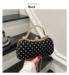 Close-up of black polka dot evening bag with gold handle and sparkling crystal clasp