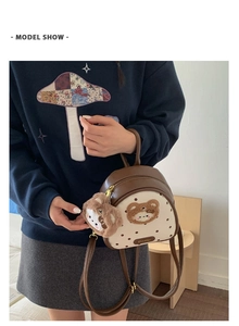 Polished brown and beige polka dot backpack with a cute plush bear charm on a model