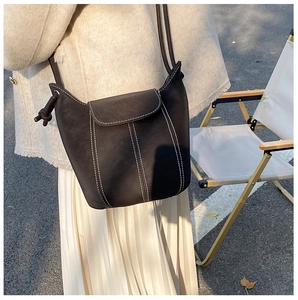 Detail of dark brown bucket bag with contrast stitching and knotted rope shoulder strap